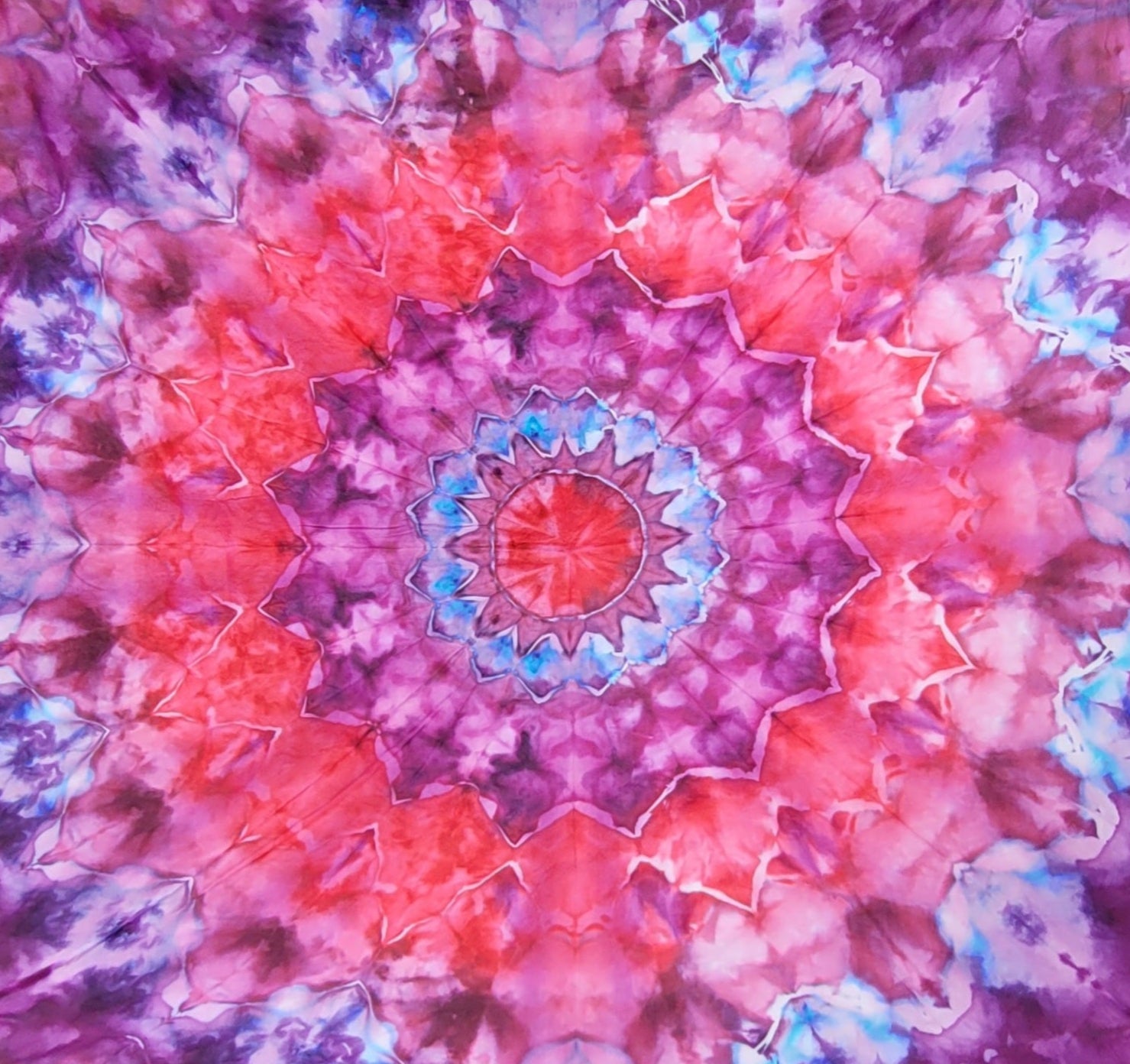 Colorful tie-dye mandala tapestry with pink and purple hues.